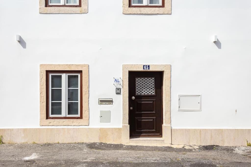 リスボンにあるA Treat in Belémの茶色のドアと窓が2つある白い建物
