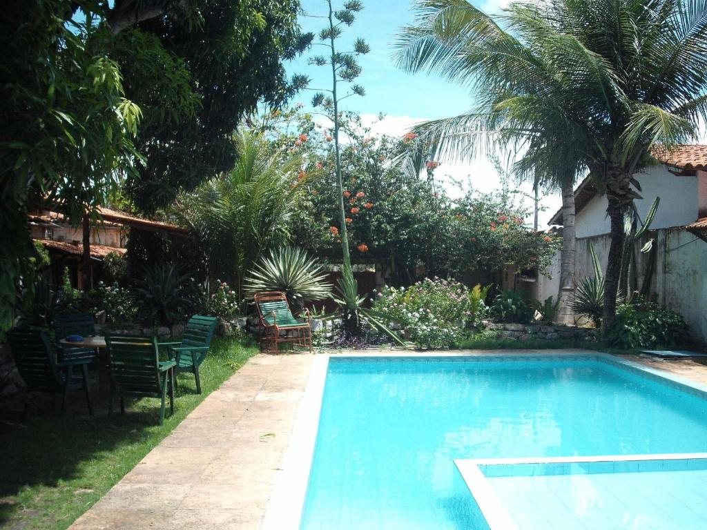 a swimming pool with chairs and a table in a yard at Pousada Chalé Suiço in Parnaíba