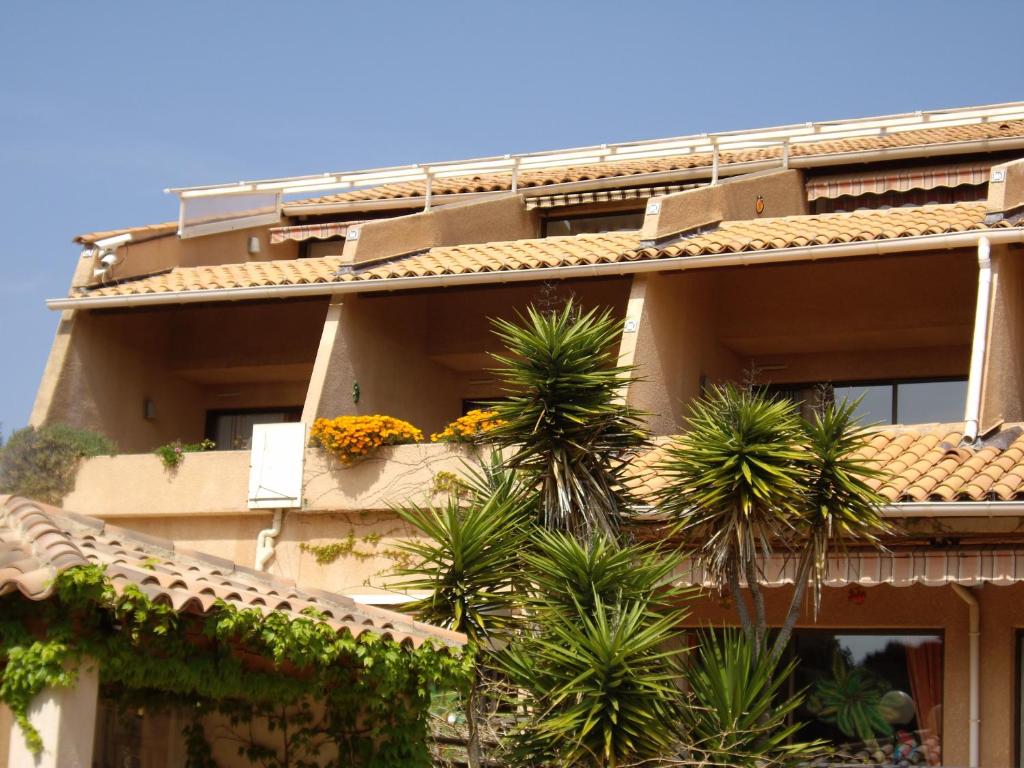 a building with palm trees in front of it at Hôtel Les Palmiers in Bormes-les-Mimosas