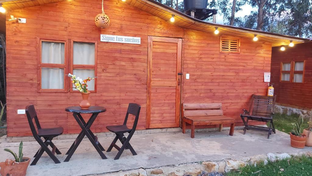 Cabaña de madera con sillas, mesa y banco en Mundo Nuevo Cabañas, en Ráquira