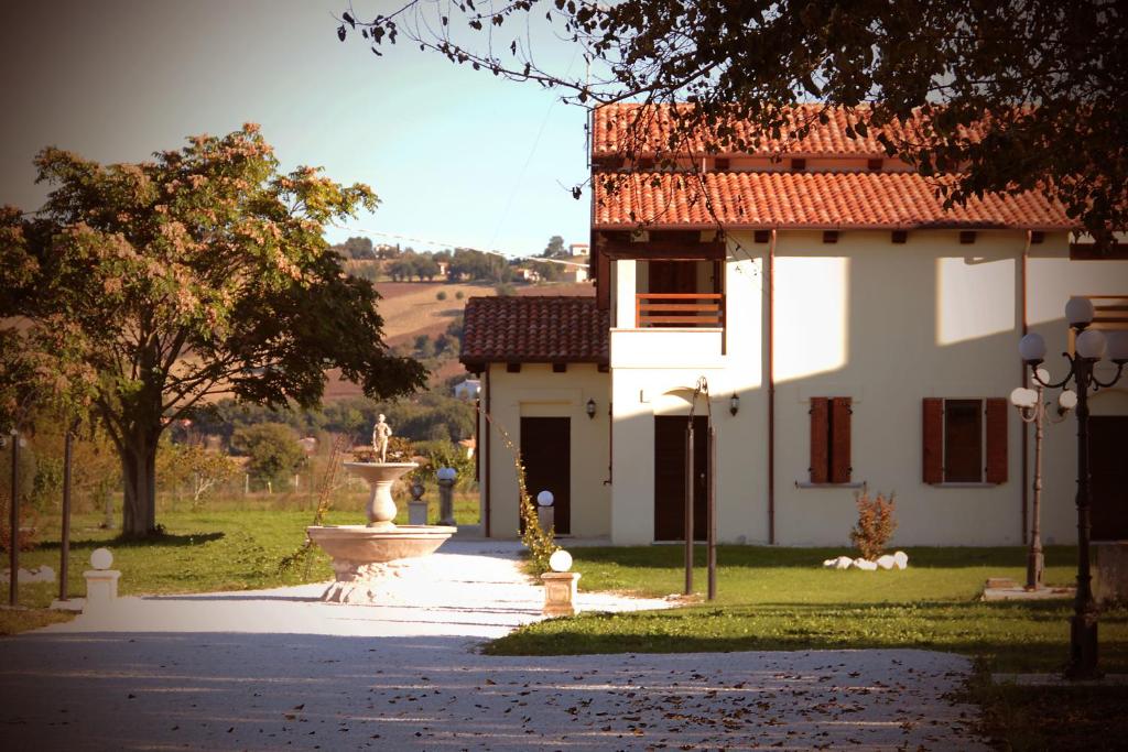 una casa blanca con una fuente frente a un patio en Agriturismo Regina di fiori, en Monte Porzio