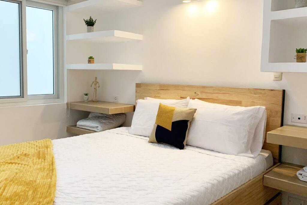 1 dormitorio con 1 cama con sábanas y almohadas blancas en Curious Family Space D1, en Guatemala