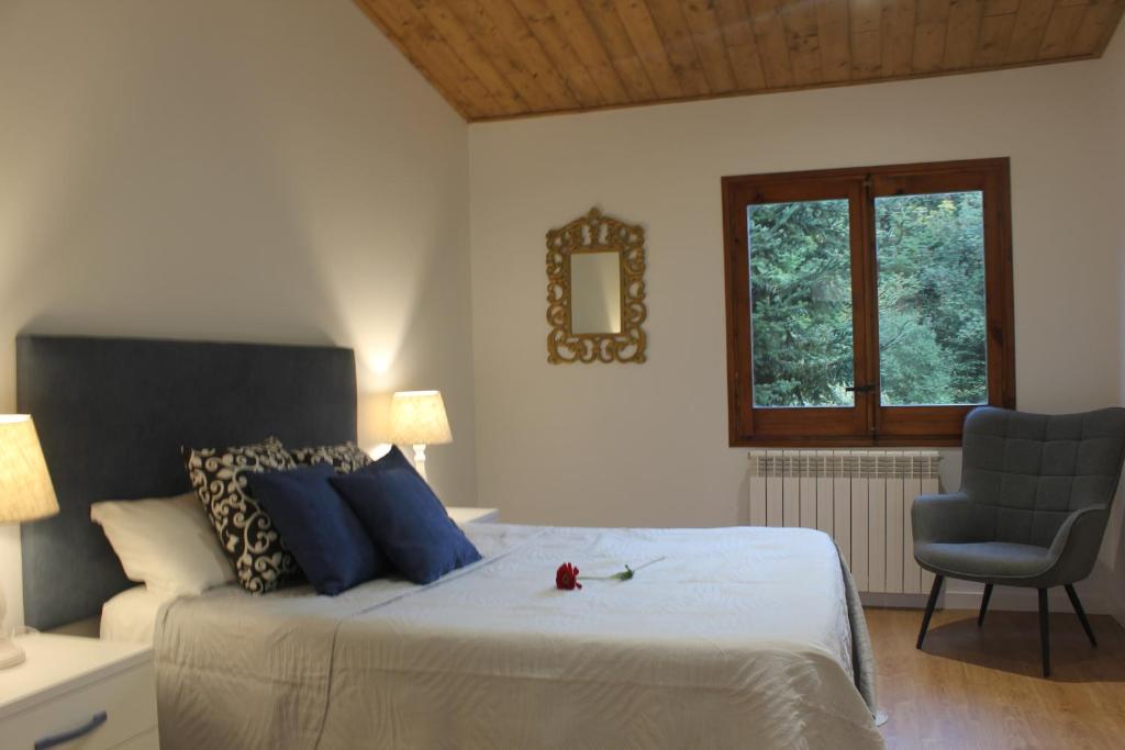 a bedroom with a bed with blue pillows and a chair at Apartamentos CAN GUSI in Ribes de Freser