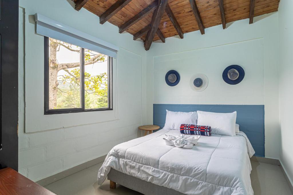a bedroom with a large white bed with a window at Soy Local Guatape in Guatapé