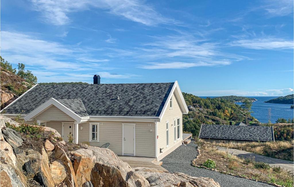 a white house with a gray roof on a hill at Beautiful Home In Risør With Kitchen in Risør