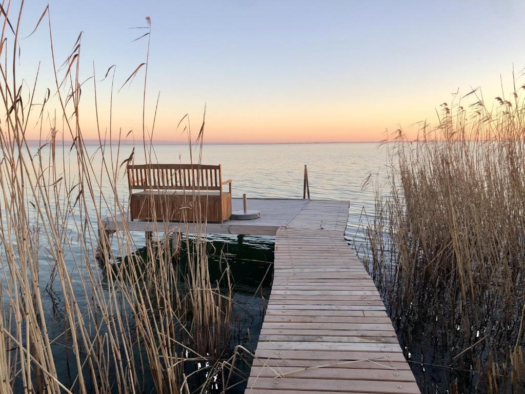 a wooden dock with a bench sitting on the water at Nádliget Vendégház in Ábrahámhegy