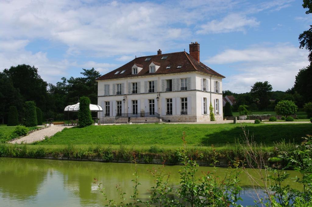 a large white house with a pond in front of it at Château de Pommeuse in Pommeuse