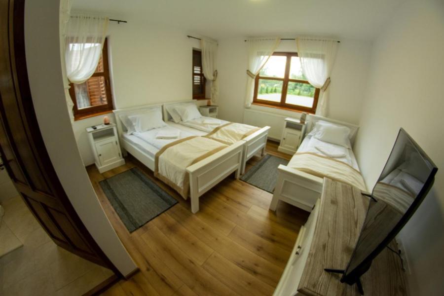 a view of a bedroom with two beds and a tv at Átalvetős Agropanzió in Morăreni