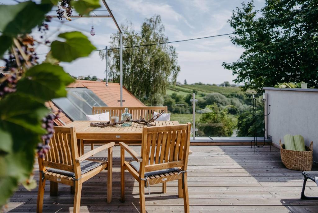 einen Holztisch und Stühle auf einer Holzterrasse in der Unterkunft Wein Cottage Kellerstöckl in Eisenberg an der Pinka