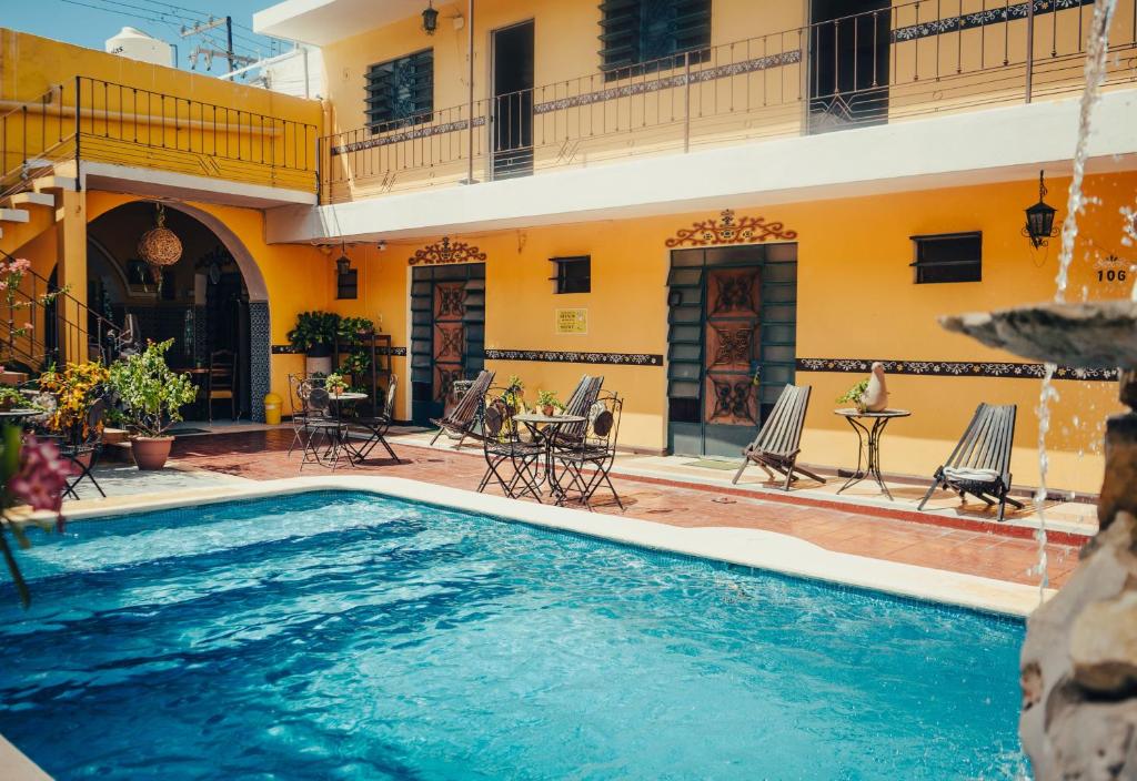 a pool in front of a house with chairs and a table at Hotel Mucuy in Mérida