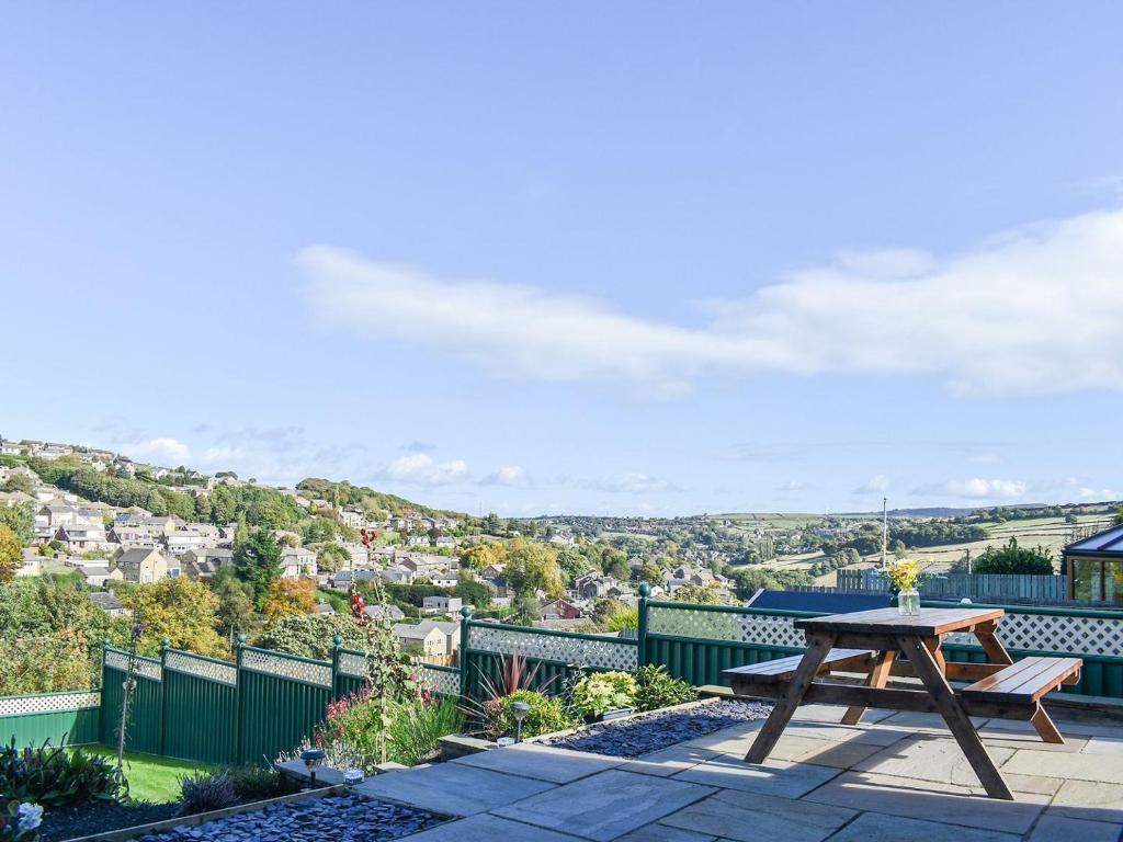 a picnic table on a patio with a view of a city at Holme Valley Cottage in Holmfirth