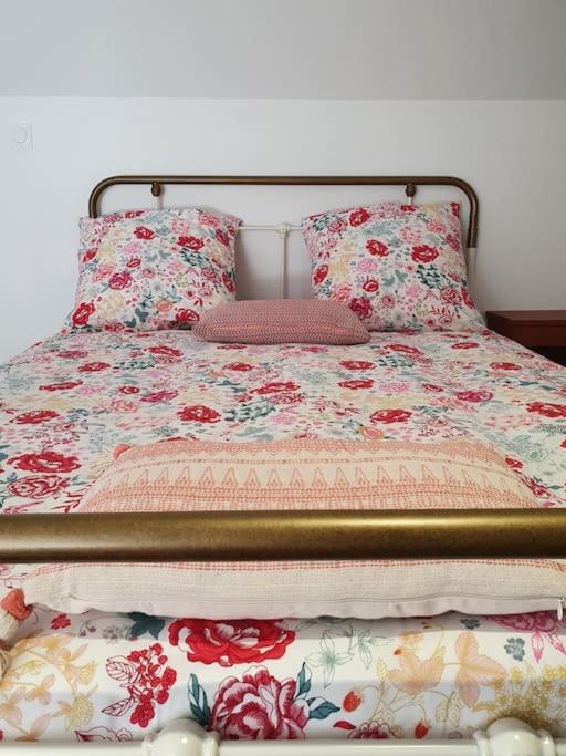 a bed with a floral bedspread and pillows on it at Pavillon d&#39;Aÿ cottage Champagne - Label Green Key in Ay
