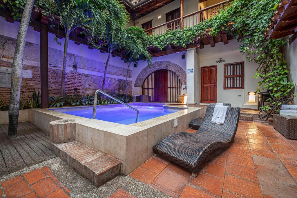 ein Pool mit zwei Korbstühlen neben einem Gebäude in der Unterkunft Casa BuGo in Cartagena de Indias
