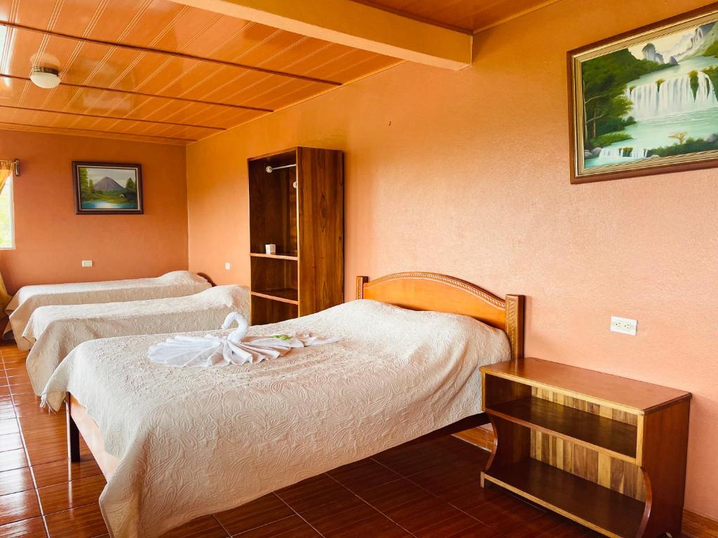 a room with two beds and a table in it at Los Tucanes Lodging in El Castillo de La Fortuna