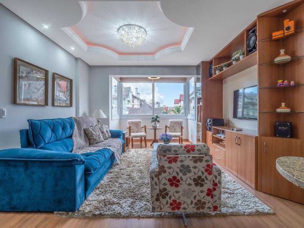 uma sala de estar com um sofá azul e uma mesa em Fascino 302 - Apartamento 600 metros Rua Coberta de Gramado em Gramado