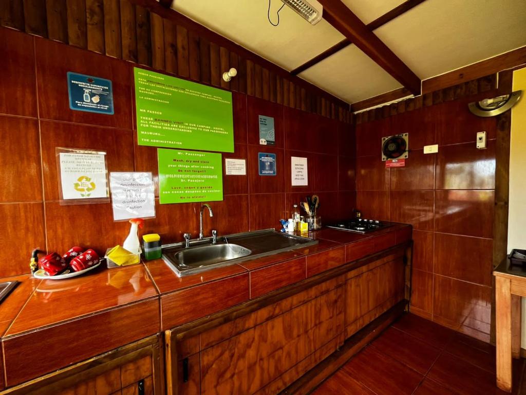 una cucina con lavandino e parete in legno di Camping Hostal Tipanie Moana Aeropuerto Centro a Hanga Roa