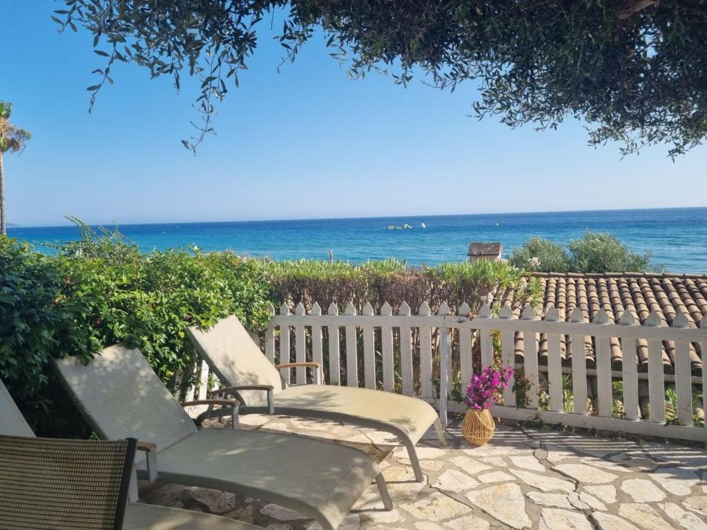 zwei Stühle neben einem Zaun mit dem Meer in der Unterkunft Corfu Dream Holidays Villas 2-4 in Glyfada