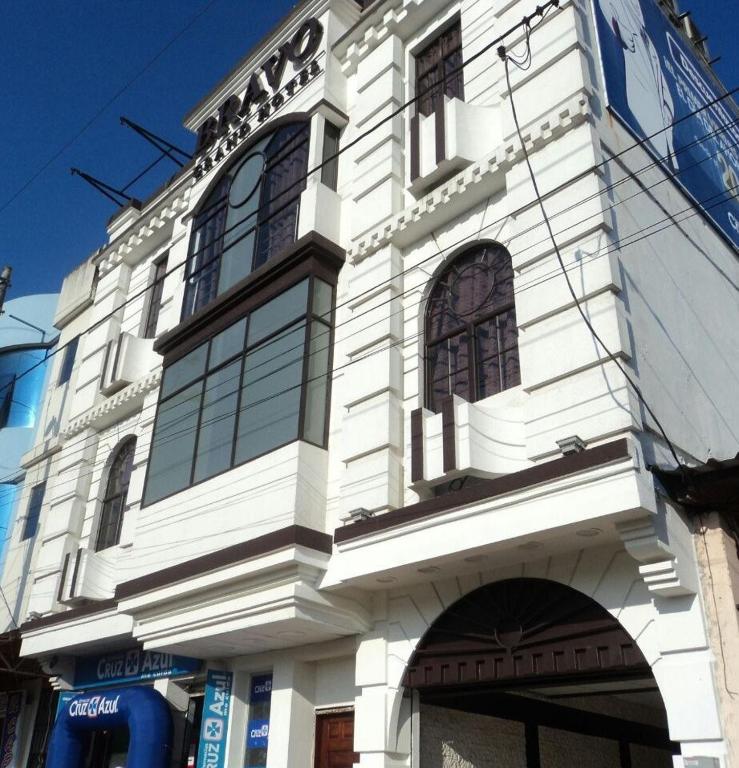 a white building with windows on a street at Hotel - Bravo Grand Hotel in Quevedo