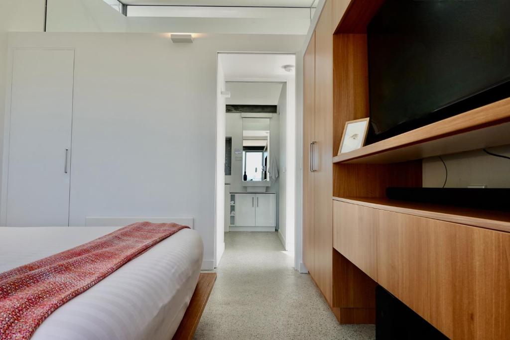 a bedroom with a bed and a flat screen tv at Eaglehawk Pavilions in Eaglehawk Neck