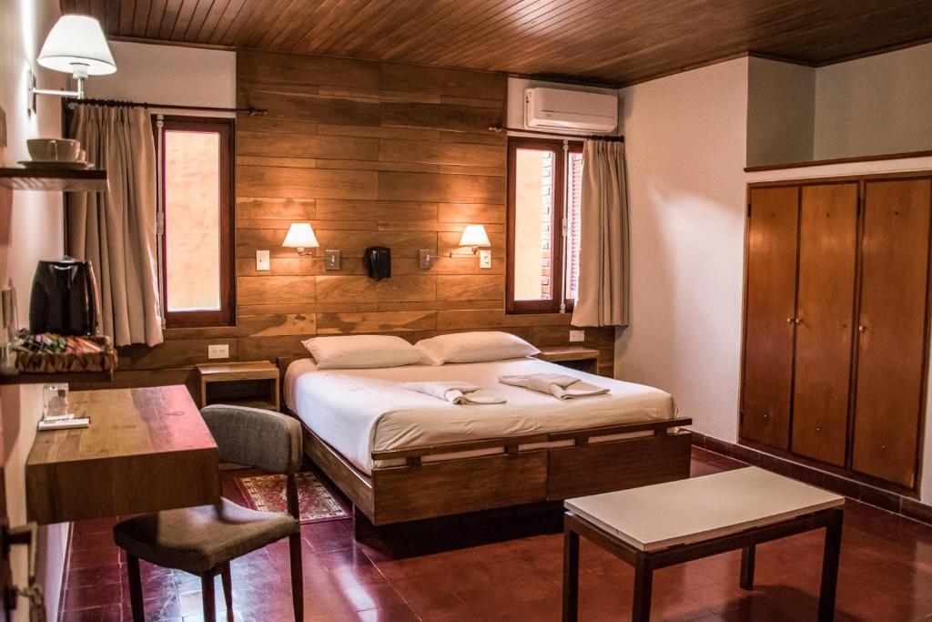 a bedroom with a bed and a table and chairs at Hotel Cuatro Pinos in Oberá