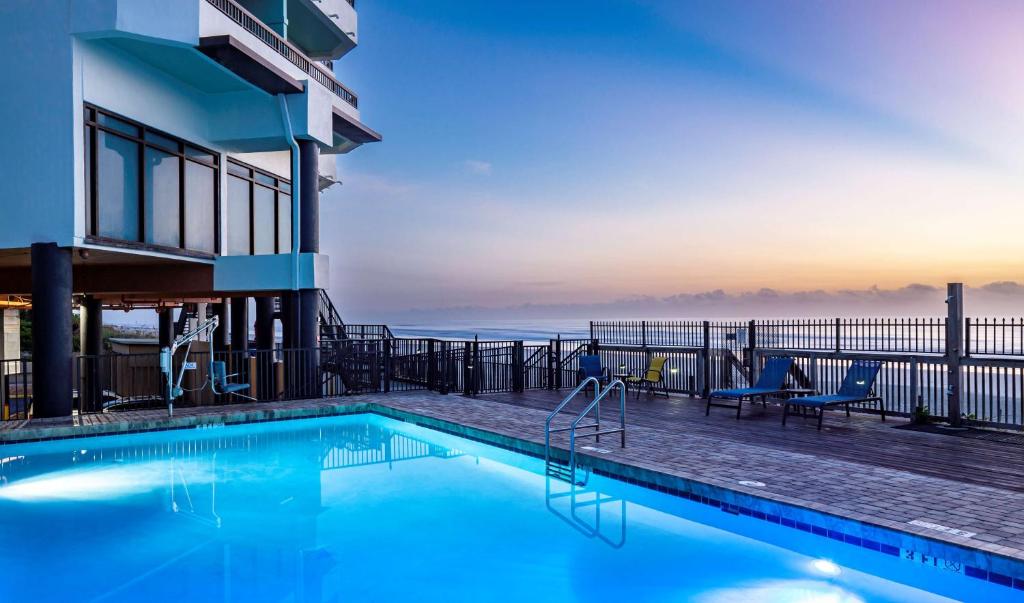 a pool with a view of the ocean from a hotel at Best Western New Smyrna Beach Hotel & Suites in New Smyrna Beach