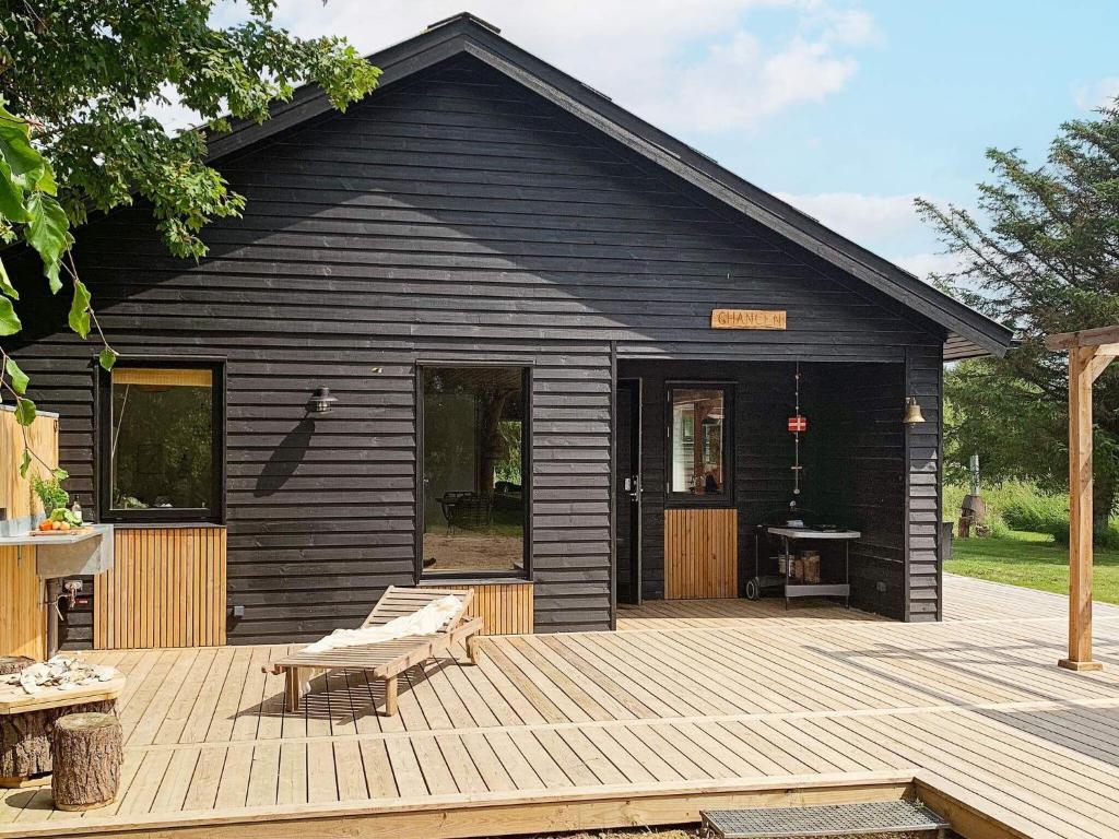 ein schwarzes Haus mit einer Holzterrasse davor in der Unterkunft 10 person holiday home in Vinderup in Vinderup
