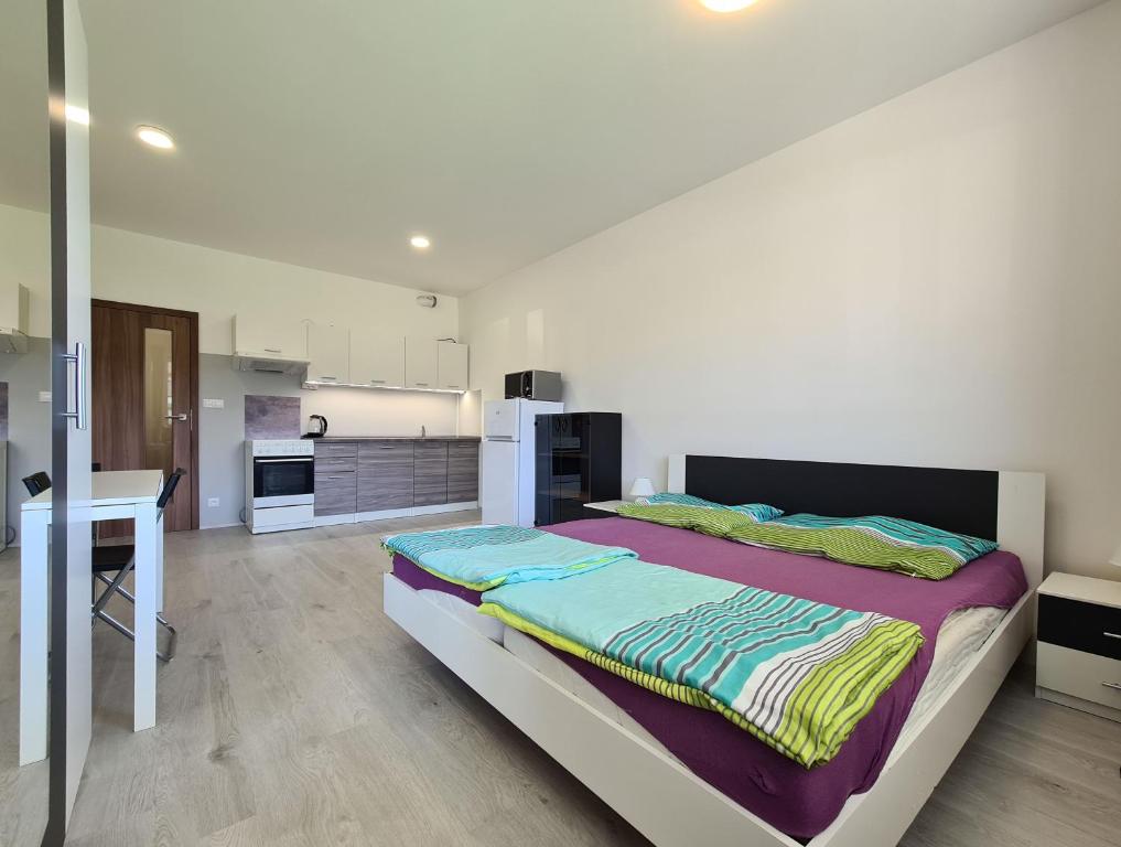 a bedroom with a large bed and a kitchen at Cozy and modern apartment near Brno city center in Husovice