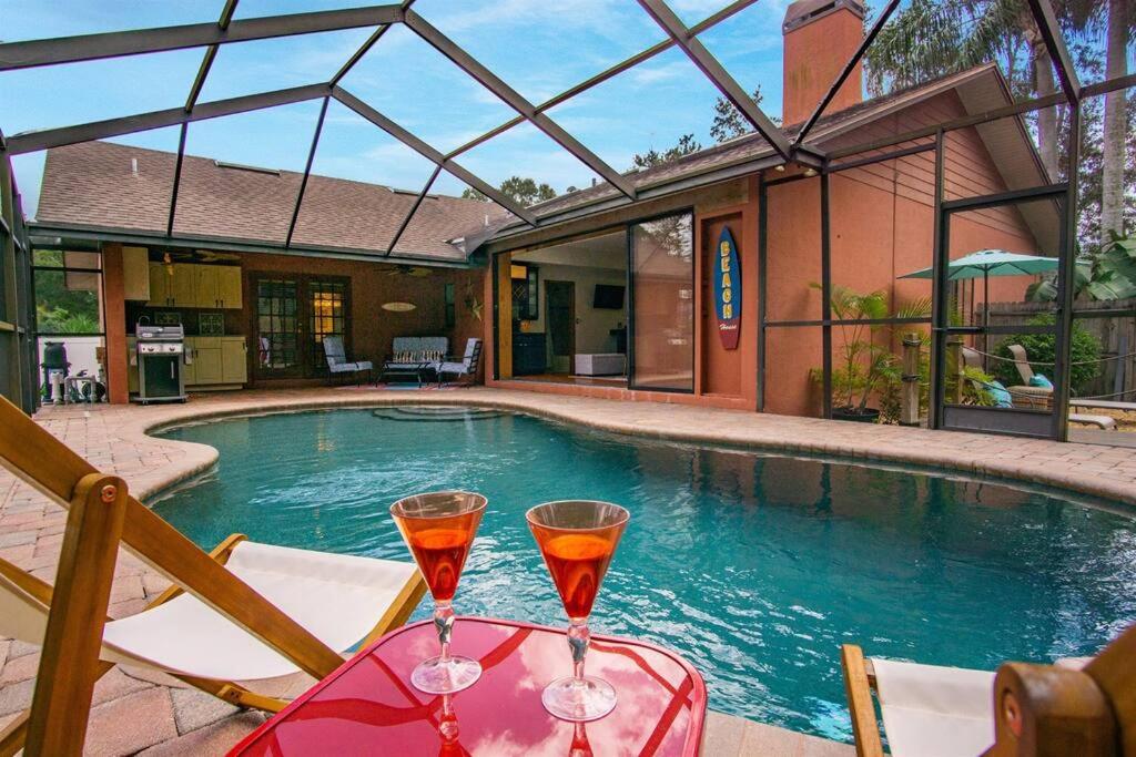 two glasses of wine sitting on a table next to a swimming pool at Family Friendly Pool Paradise Retreat Near Beaches in Palm Harbor