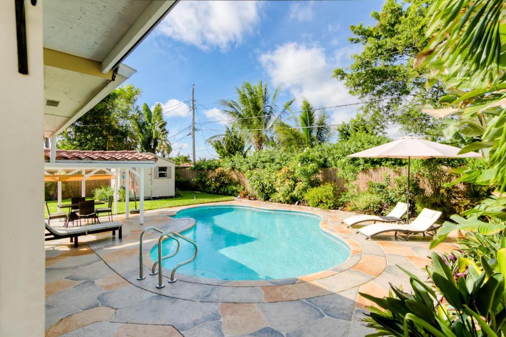 a swimming pool with a patio furniture and an umbrella at Casa Contenta in Fort Lauderdale
