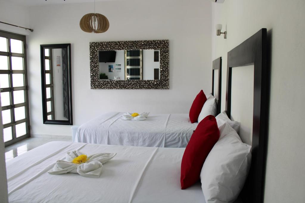 a bedroom with two beds with red pillows and a mirror at Casa Zazil in Bacalar