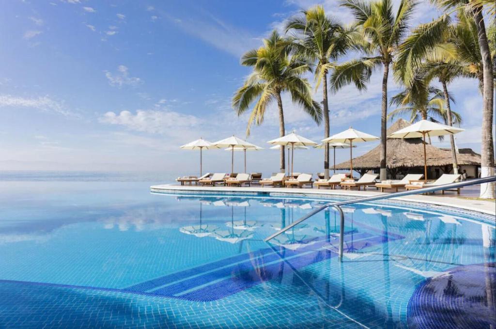 a swimming pool with umbrellas and the ocean at Condo at Krystal Grand Resort in Bucerías