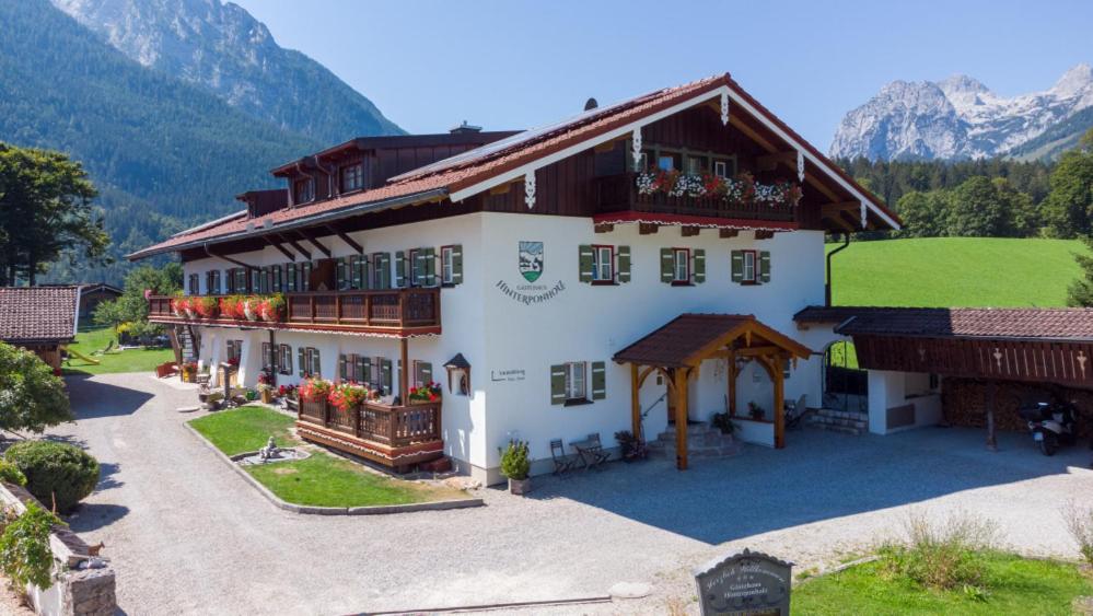 un gran edificio blanco con montañas en el fondo en Gästehaus Hinterponholz en Ramsau