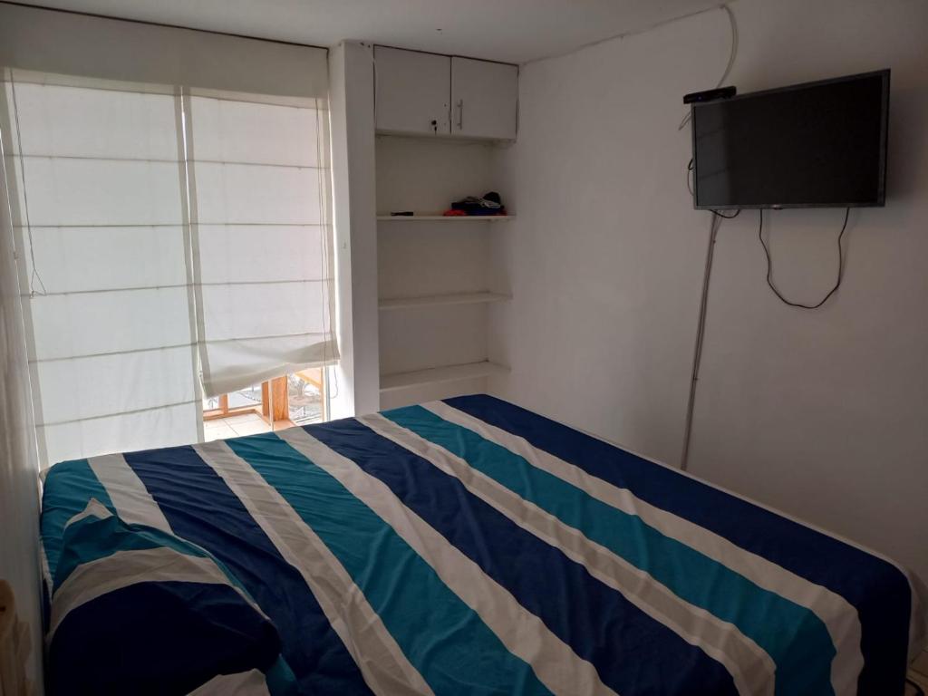 ein Schlafzimmer mit einem Bett mit gestreifter Decke und einem TV in der Unterkunft Minidepartamento en San Bartolo - VISTA AL MAR in San Bartolo