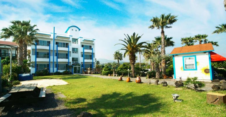 a building with palm trees in front of a yard at Hodo House in Seogwipo