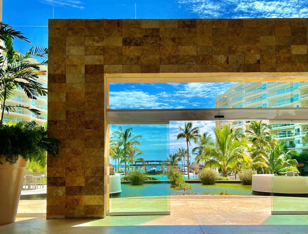 un edificio con vistas a una piscina y palmeras en Beachfront Condo DelCanto Resort, en Nuevo Vallarta 
