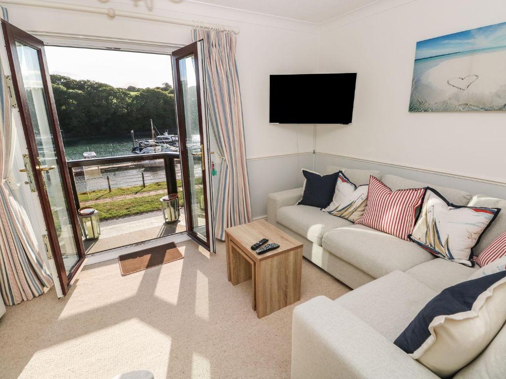 a living room with a couch and a tv and a window at Yacht Haven View in Milford Haven
