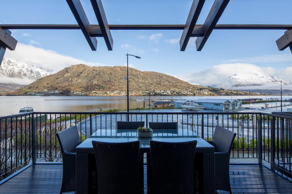 a table and chairs on a balcony with a view of a mountain at Absolute Lakefront Location - 3 bedroom apartment in Queenstown