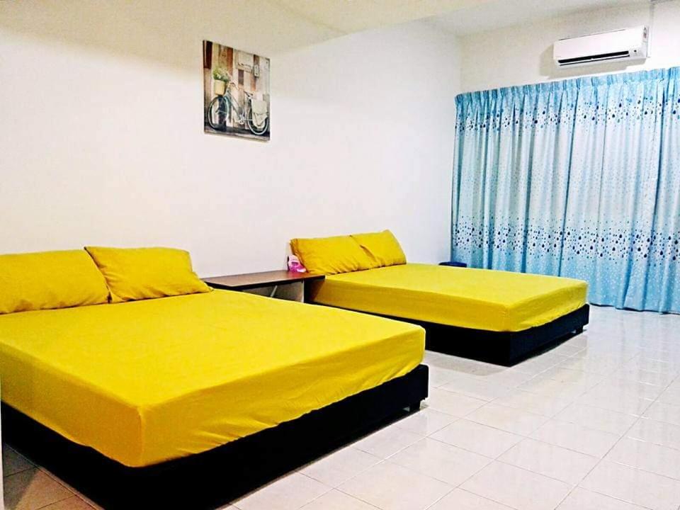duas camas num quarto com lençóis amarelos em “Alan Homestay” Pangkor Lot 10 em Kampong Sungai Udang