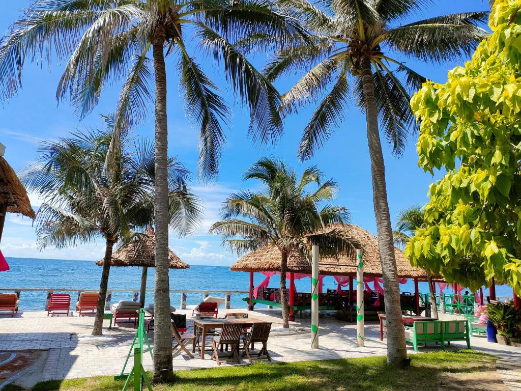 a beach with tables and palm trees and the ocean at Full Moon Beach Resort in Mui Ne