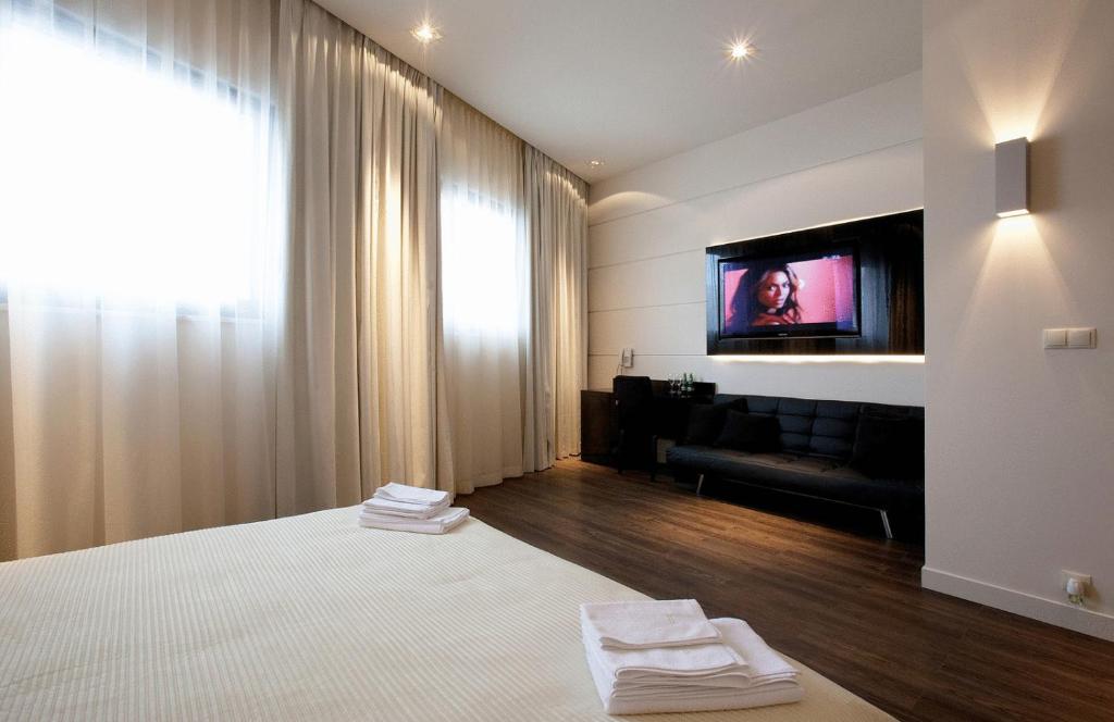 ウォミアンキにあるVilla & Spaのベッド1台、壁掛けテレビが備わるホテルルームです。
