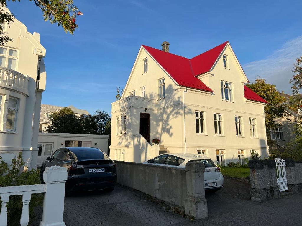 une maison blanche avec un toit rouge et deux voitures garées devant dans l'établissement Reykjavik Urban Escape 2-Bedroom Haven with Private Entrance, à Reykjavik