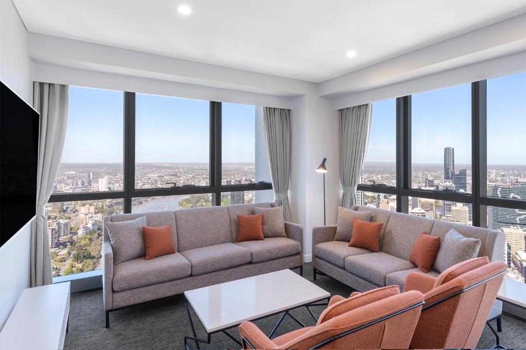 a living room with a couch and chairs and large windows at Meriton Suites Adelaide Street, Brisbane in Brisbane