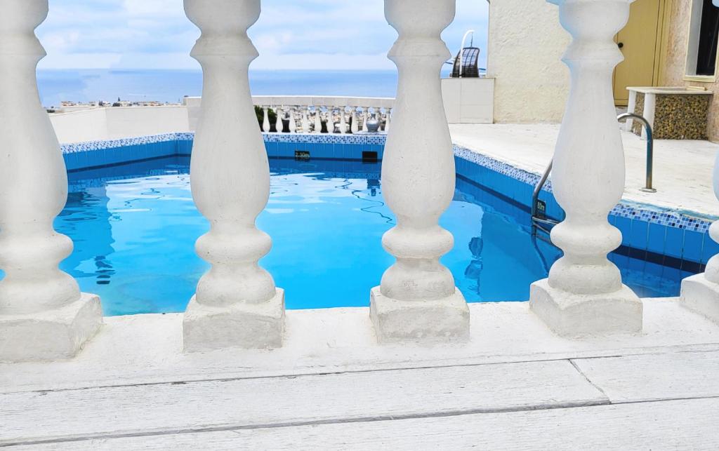 una piscina con colonne bianche e acqua blu di Room in Studio - One Room Private Suite a Hersonissos