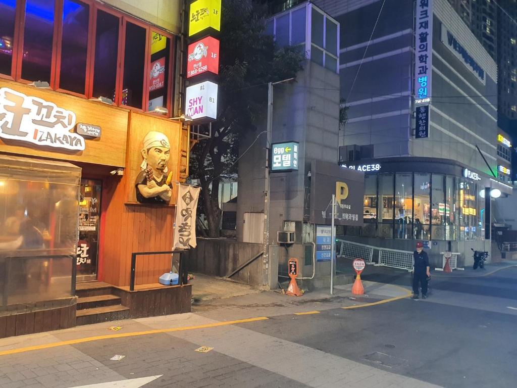 a man is walking down a city street at night at Egg Motel in Busan