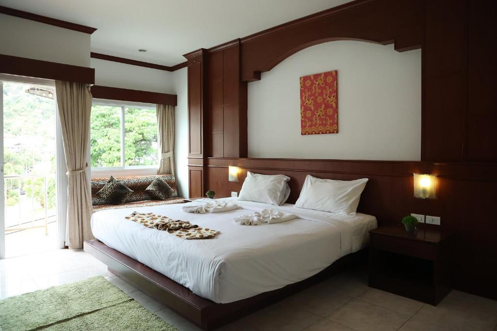 a bedroom with a large white bed with a large window at New Forest Patong in Patong Beach