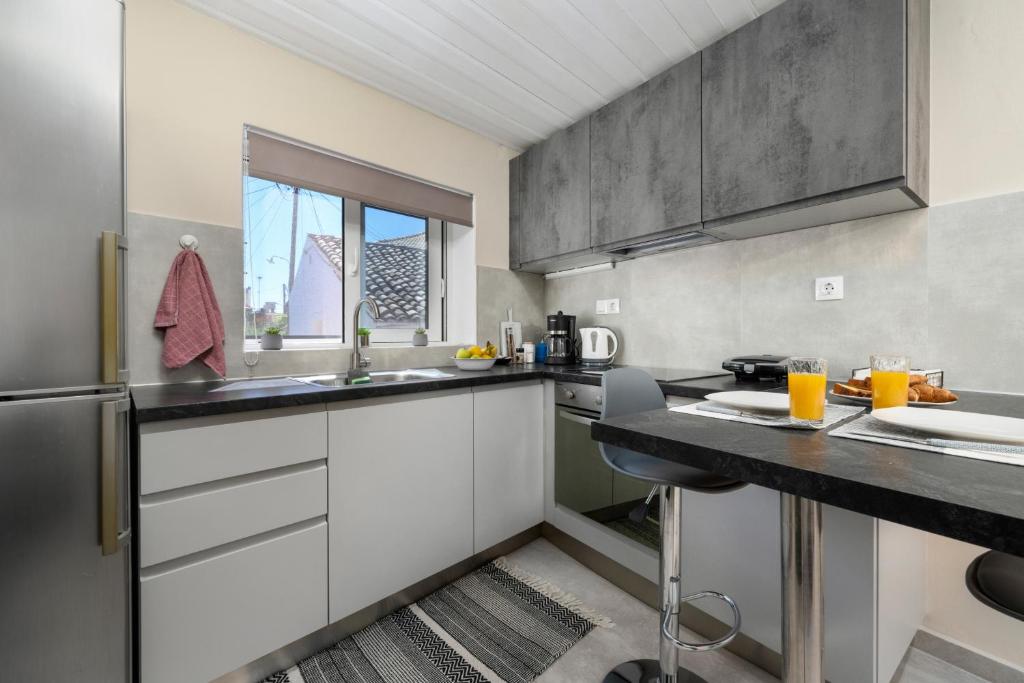 a kitchen with white cabinets and a black counter top at Ileana-Marina studio 1 in Benitses