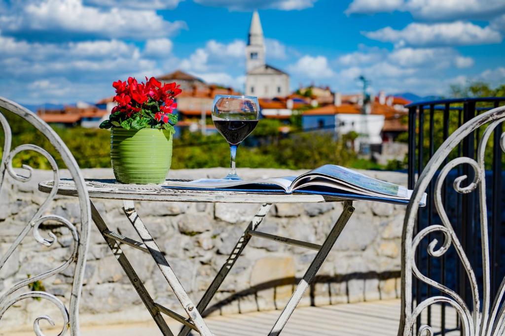 uma mesa com um copo de vinho e um vaso de flores em Karst house Žan Pliskovica em Dutovlje