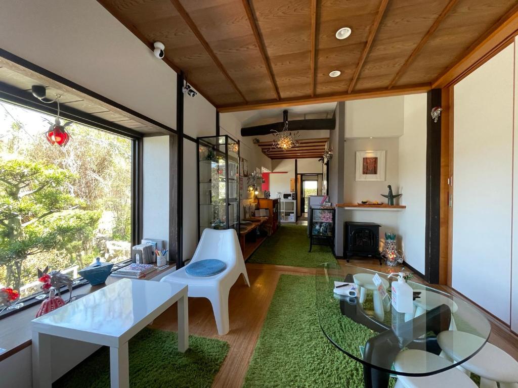 uma sala de estar com uma mesa de vidro e um quarto em Bamboo Village Guest House em Naoshima