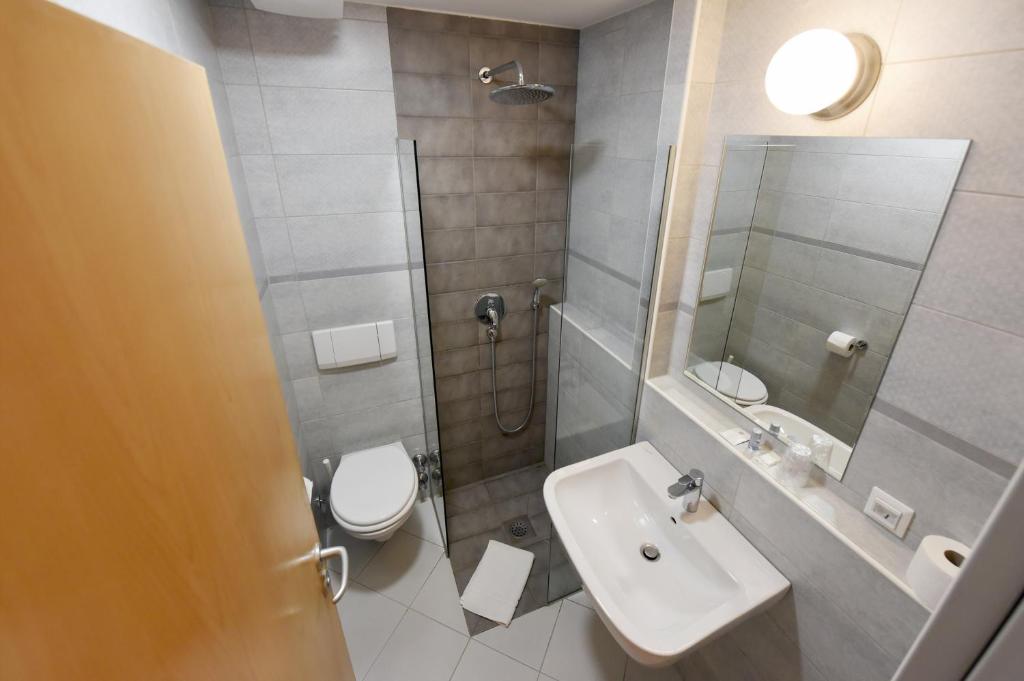 a bathroom with a toilet and a sink and a shower at Hotel Korotan in Vienna
