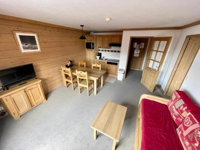 a living room with a table and chairs and a kitchen at Le Vancouver in La Plagne